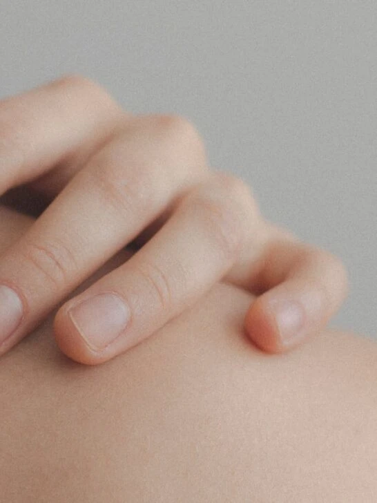 Close up of a hand on a person's shoulder with beautiful healthy skin from following healthy skin care tips