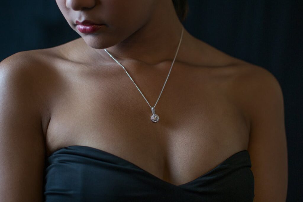 A diamond necklace on a woman wearing a sleeveless formal dress. Your outfit is one of many factors to consider when choosing the perfect necklace.