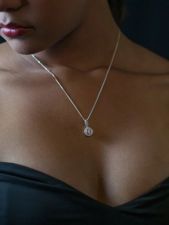 A diamond necklace on a woman wearing a sleeveless formal dress. Your outfit is one of many factors to consider when choosing the perfect necklace.