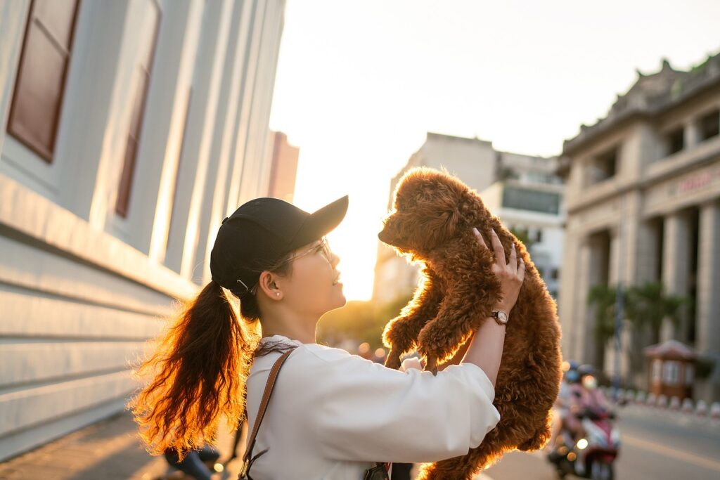 A woman holding up her dog in her arms while visiting a foreign country after traveling internationally with pets.
