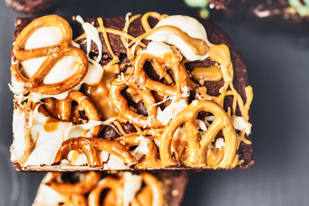 Salted Caramel + Pretzel Brownie: Classic double layer brownie with sweet 'n' sticky homemade salted caramel, finest white chocolate and topped with salted pretzels! Ticks all those taste bud notes in one hit! | by kaybeaumount