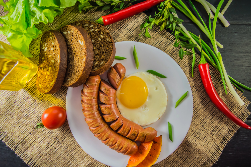 The classic English breakfast with scrambled eggs and sausages. Top view. Black background of wood. Close-up — Stock Photo, Image