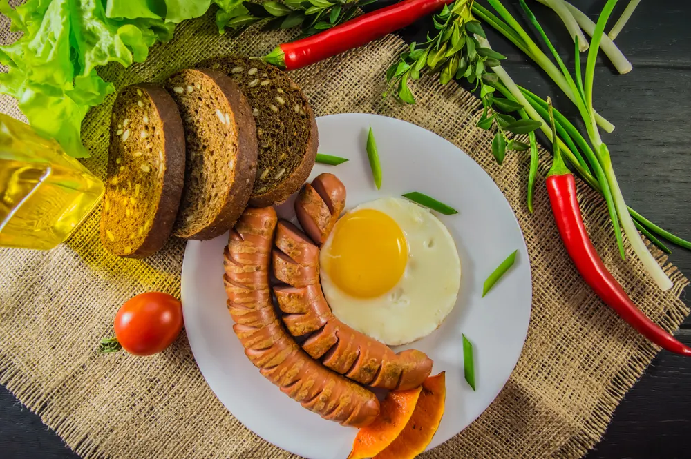 The classic English breakfast with scrambled eggs and sausages. Top view. Black background of wood. Close-up — Stock Photo, Image