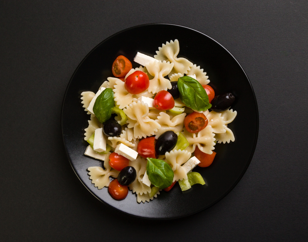 Farfalle salad on black plate — Photo