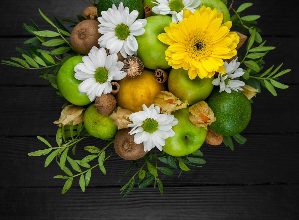 Fruit bouquet with apples, yellow flowers, kiwi fruit and avocado