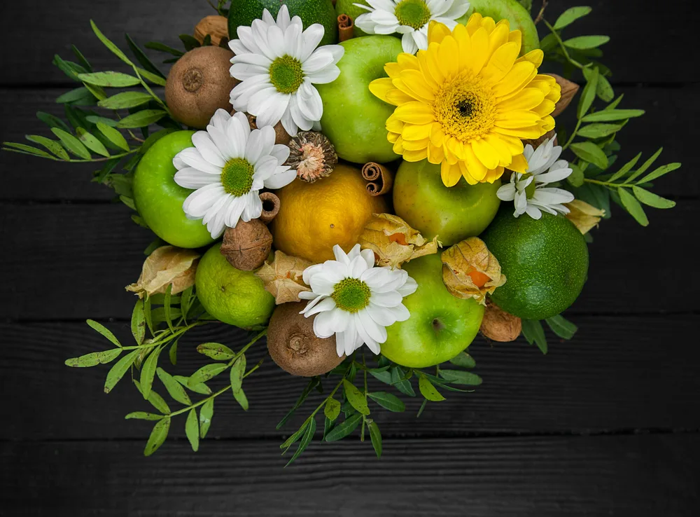 Fruit bouquet with apples, yellow flowers, kiwi fruit and avocado