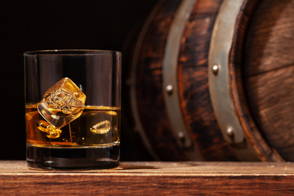 Scotch whiskey glass and old wooden barrel