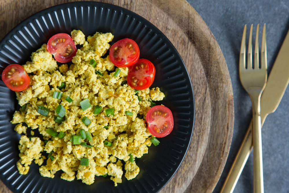 Tofu scramble with tomatoes and greens on toast on a plate