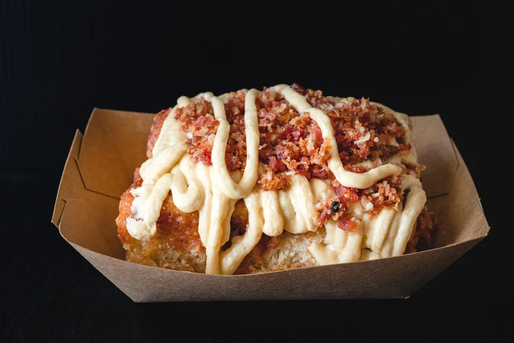 Maple Bacon Frosted cinnamon roll close up on black background — Photo