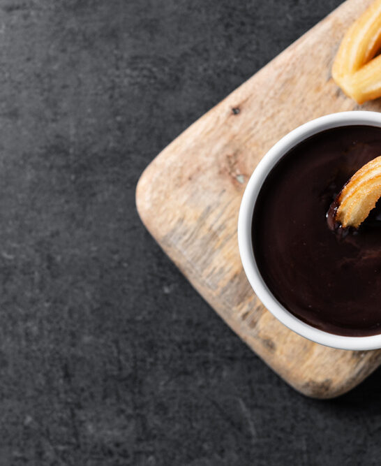 Traditional Spanish churros with hot chocolate on black slate