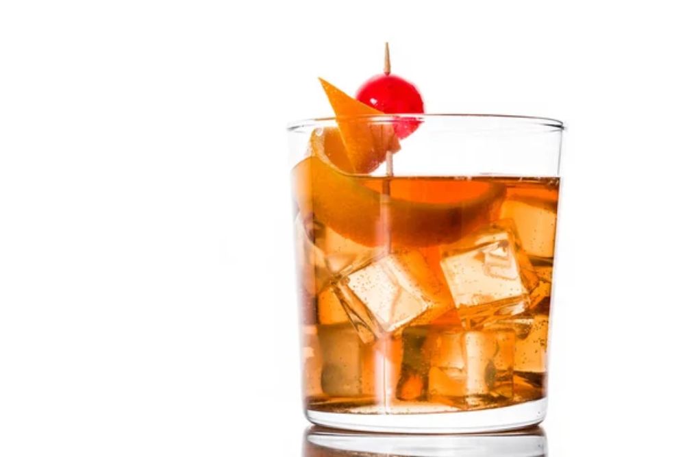 Old fashioned cocktail with orange and cherry isolated
