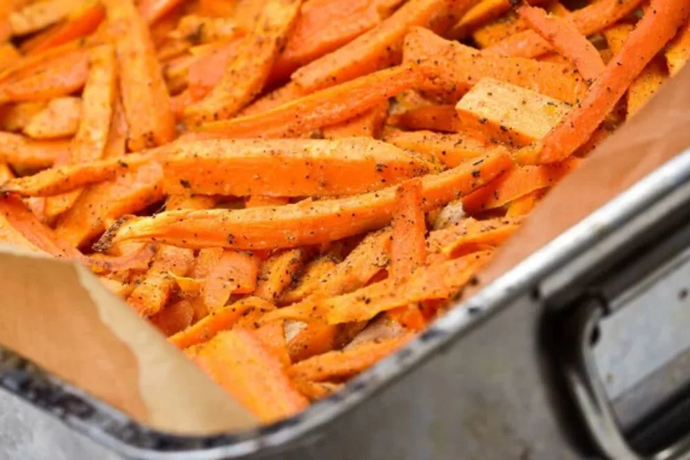 Close-up of homemade carrot chips on baking paper in an old baking tray. Vegetarian - vegan healthy meal. — Stock Photo, Image
