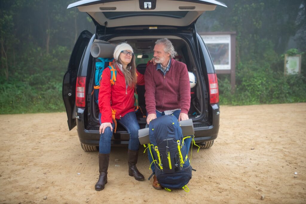 A couple sitting in the back of their SUV about to go hiking after taking steps on funding your dream retirement lifestyle