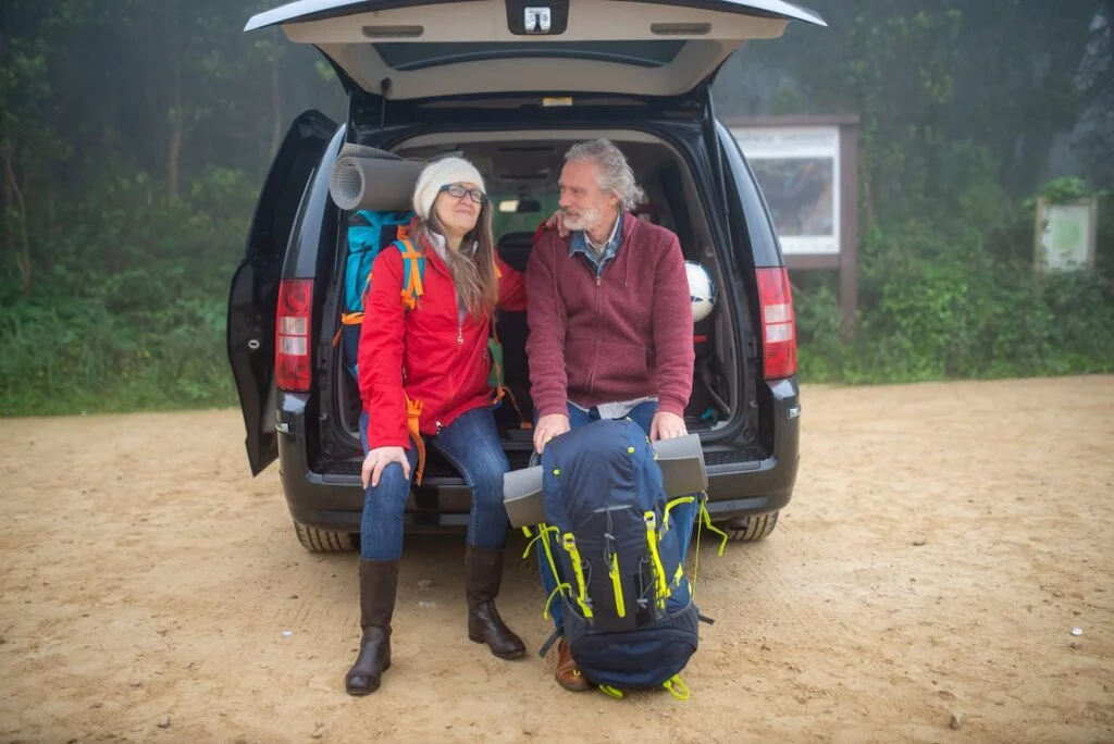 A couple sitting in the back of their SUV about to go hiking after taking steps on funding your dream retirement lifestyle