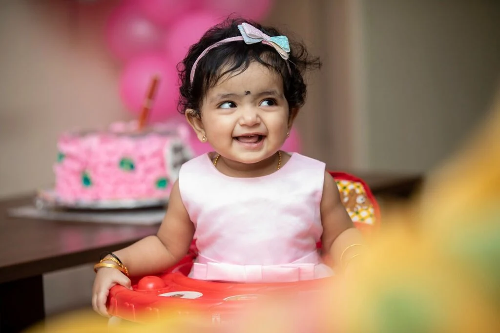 A little girl with a cake behind her posing for her birthday. Use these tips on ways to personalize your kid’s birthday party