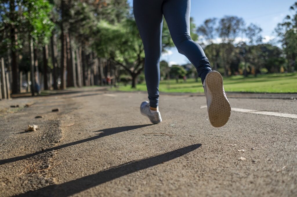Back view of a person running with focus on their feet, showing someone exercising with hearing aids for an active lifestyle.