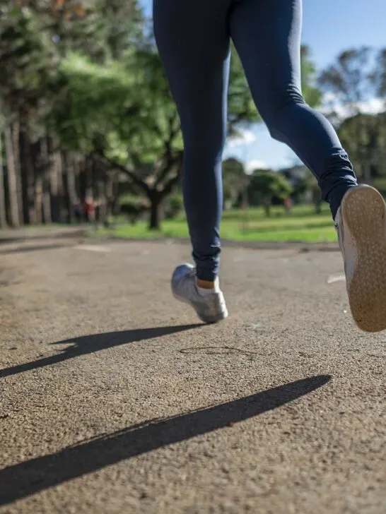 Back view of a person running with focus on their feet, showing someone exercising with hearing aids for an active lifestyle.