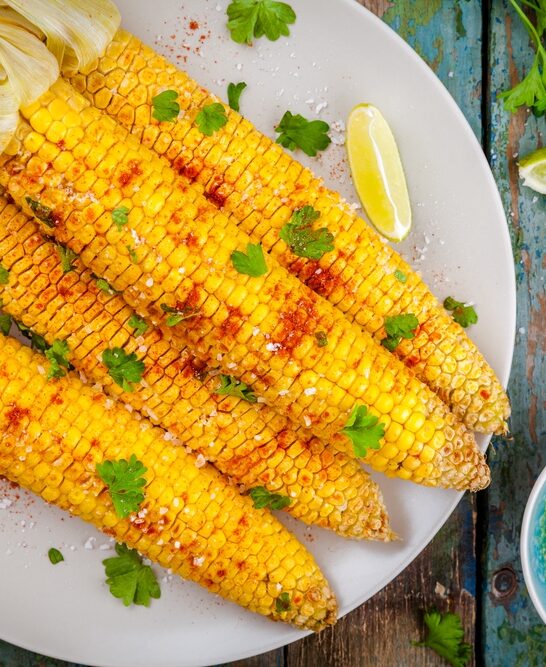 Baked sweet corn cobs with herb butter and lime — Stock Photo, Image