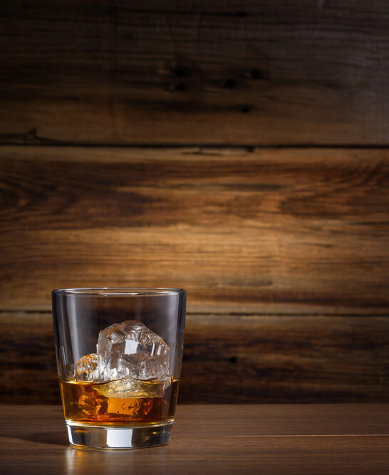 Glass of whiskey with ice on a wooden background — Stock Photo, Image