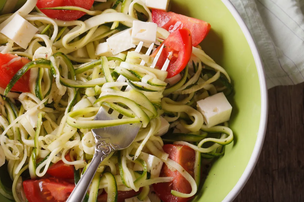 Zucchini pasta with feta and tomatoes macro. horizontal top view — Stock Photo, Image