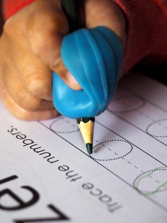 A child learning to write with the help of an assistant working in Early Childhood Career Paths Nobody Talks About