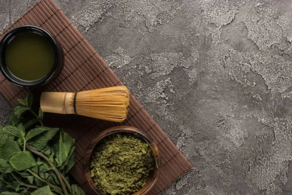 Top view of traditional matcha tea with whisk on bamboo mat