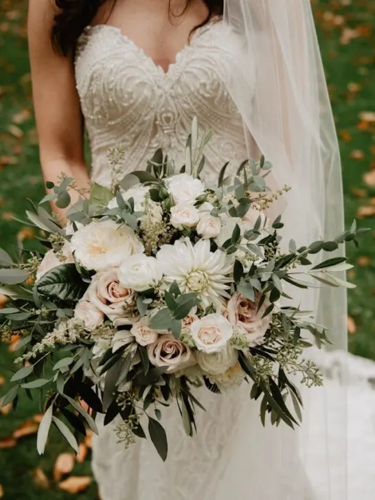 a gorgeous bouquet of flowers held by a lady in a wedding gown