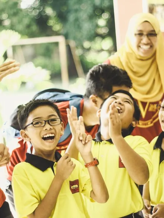A group of kids and teachers laughing in a class that uses inclusive teaching strategies
