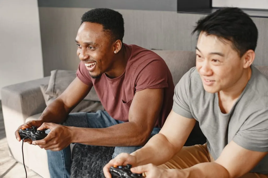 two guys sitting on the couch with game controllers playing video games for foodies