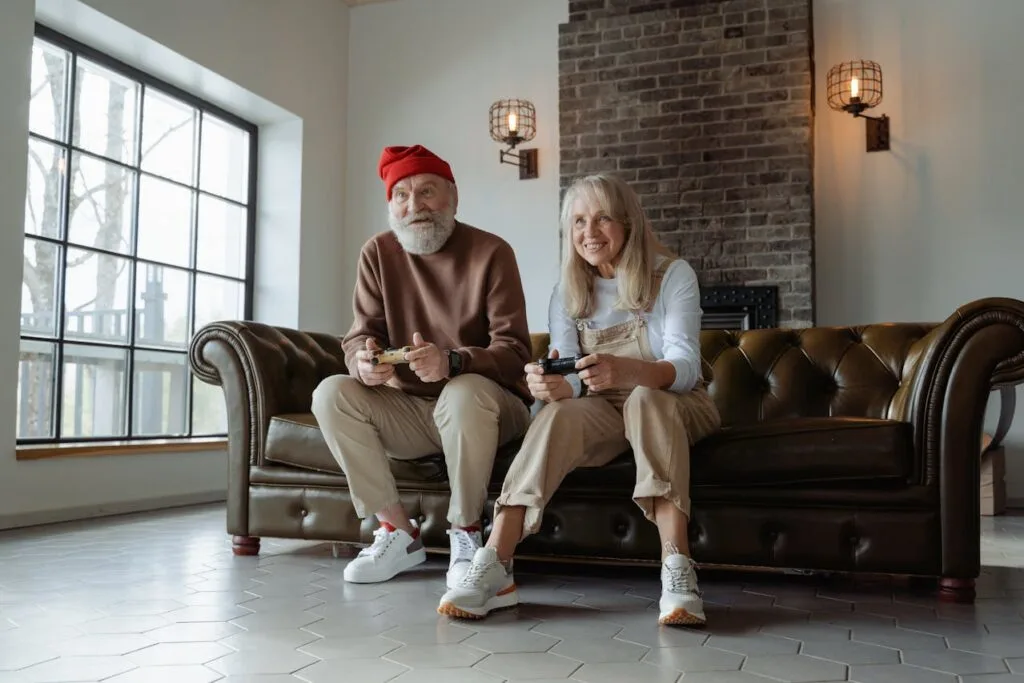 An older couple playing video games together sitting on a couch