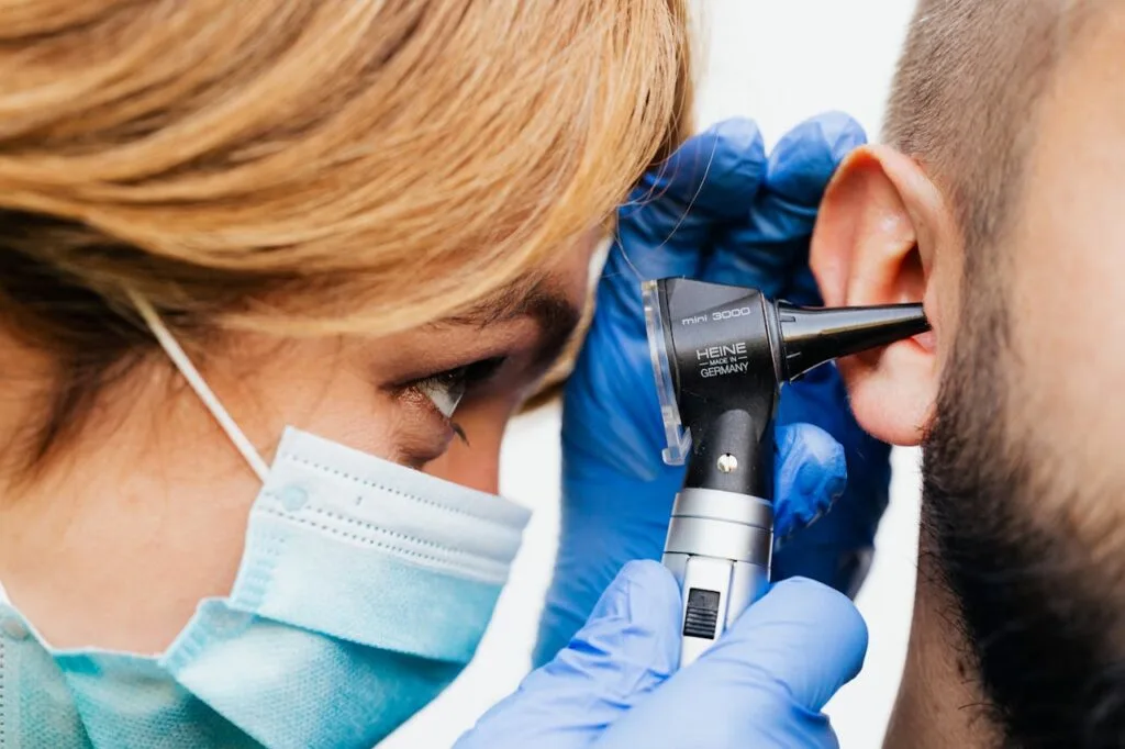 A doctor looking in her patient's ear. Learn the 9 warning signs you should have your ears examined soon
