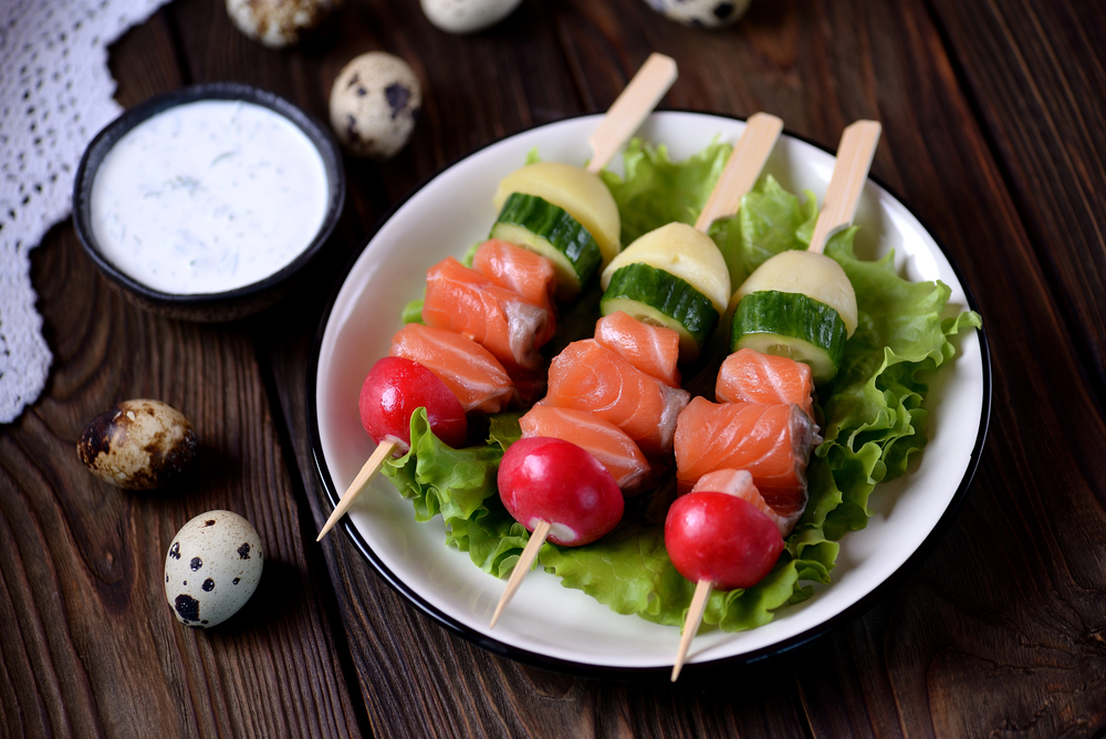 Appetizer on wooden skewers from lightly salted salmon, boiled potatoes, cucumber and radish. — Stock Photo, Image