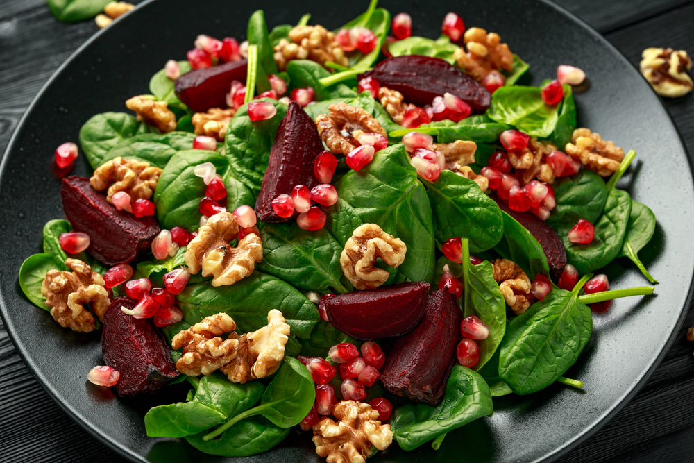 Healthy Beet Salad with fresh sweet baby spinach, pomegranate seeds and candy walnut. healthy Vegan vegetarian, plant based food — Stock Photo, Image