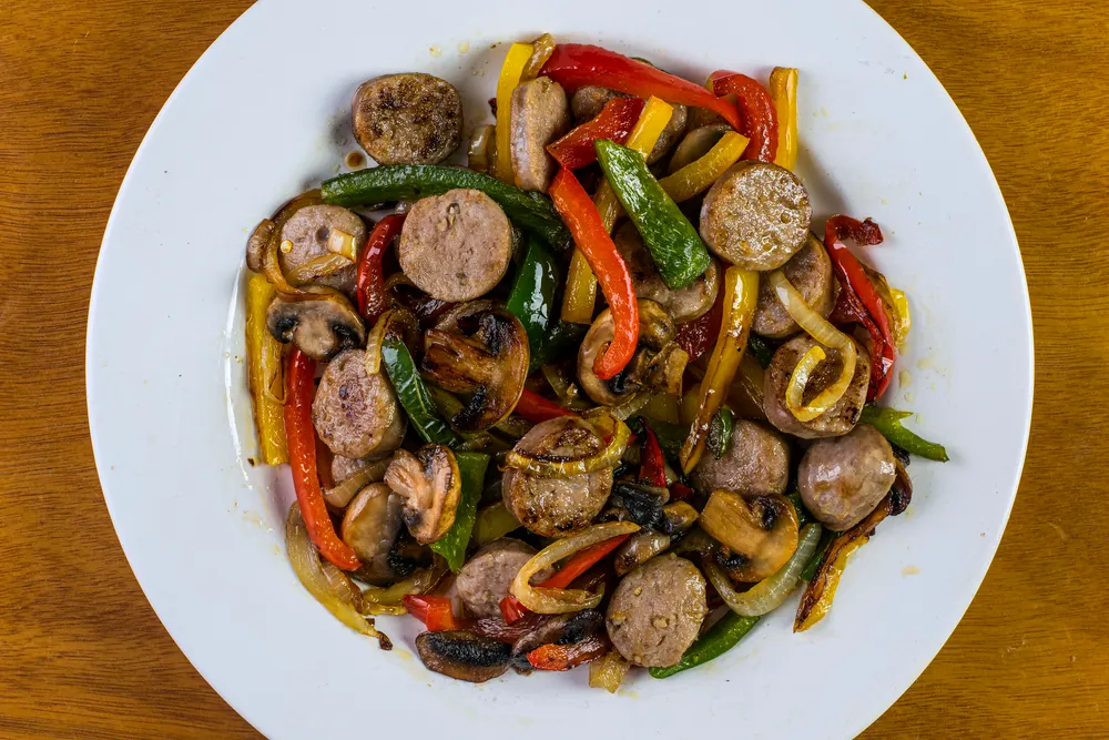 a dish consisting of sausage, onions and pepeppers with mushrooms