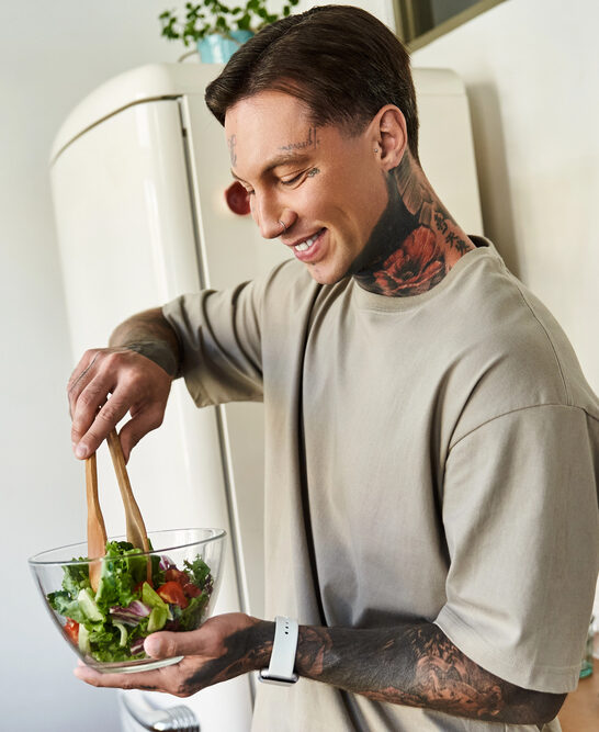 Confident Young Man Stirs Vibrant Salad Glass Bowl Enjoying His — Stock Photo, Image