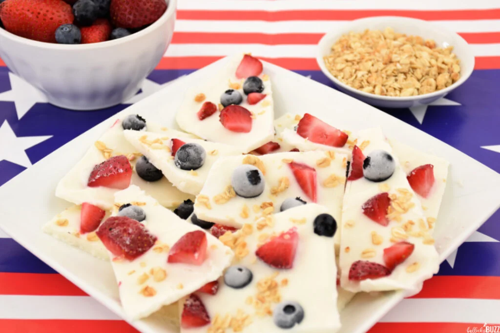 Pieces of 4th of July Frozen Yogurt Bark on a white plate sitting on an American flag tablecloth