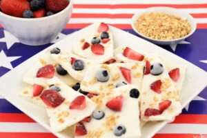 Pieces of 4th of July Frozen Yogurt Bark on a white plate sitting on an American flag tablecloth