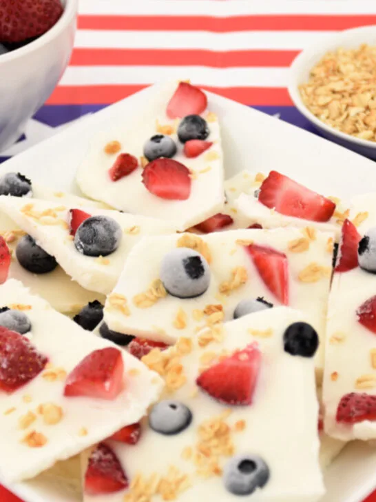 Pieces of 4th of July Frozen Yogurt Bark on a white plate sitting on an American flag tablecloth