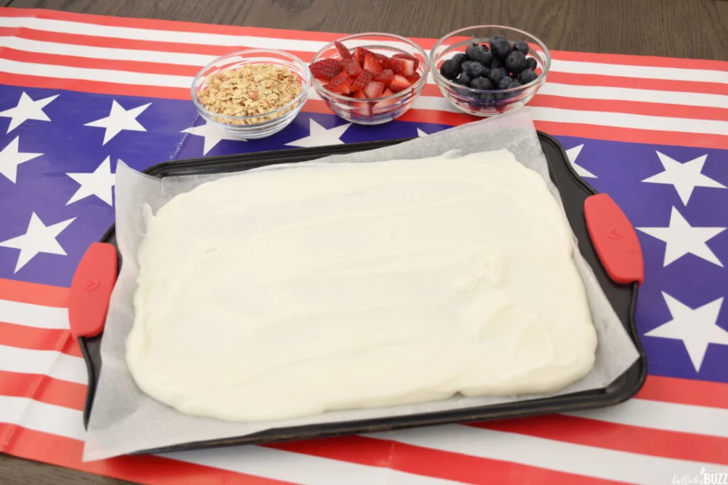 Vanilla Greek yogurt is spread out on a parchment paper-lined baking sheet
