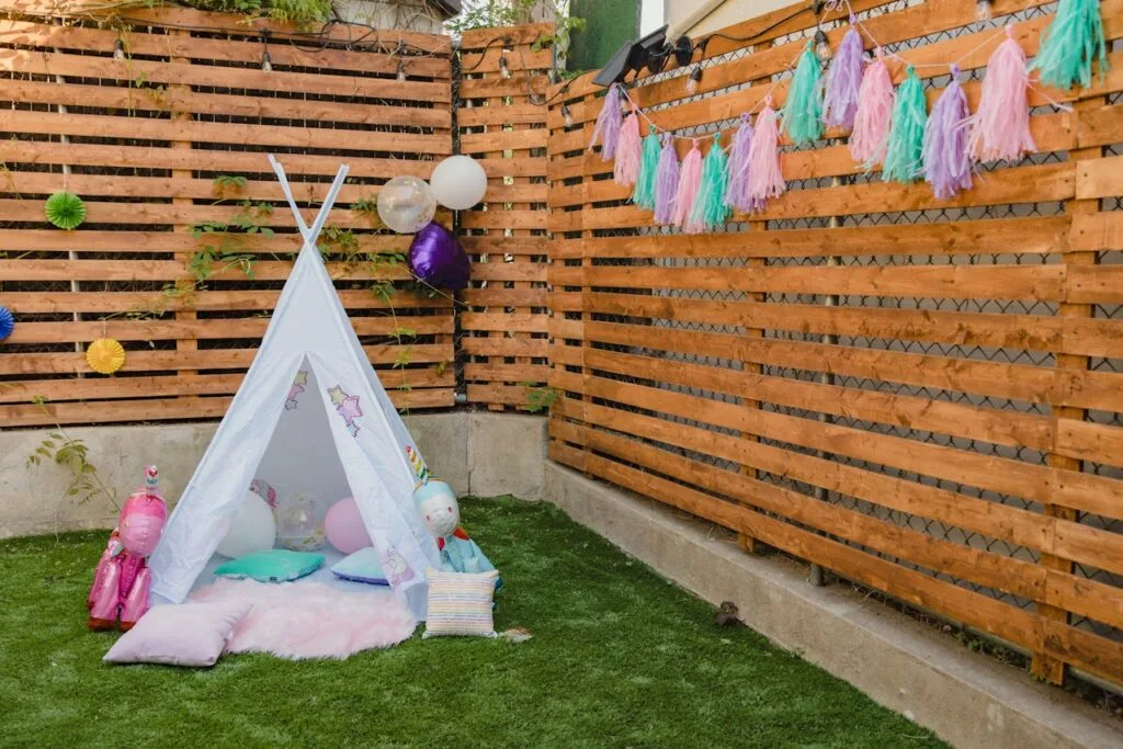 Balloons and pom-poms on a fence behind a tent are budget-friendly summer party decorations that make a big impact