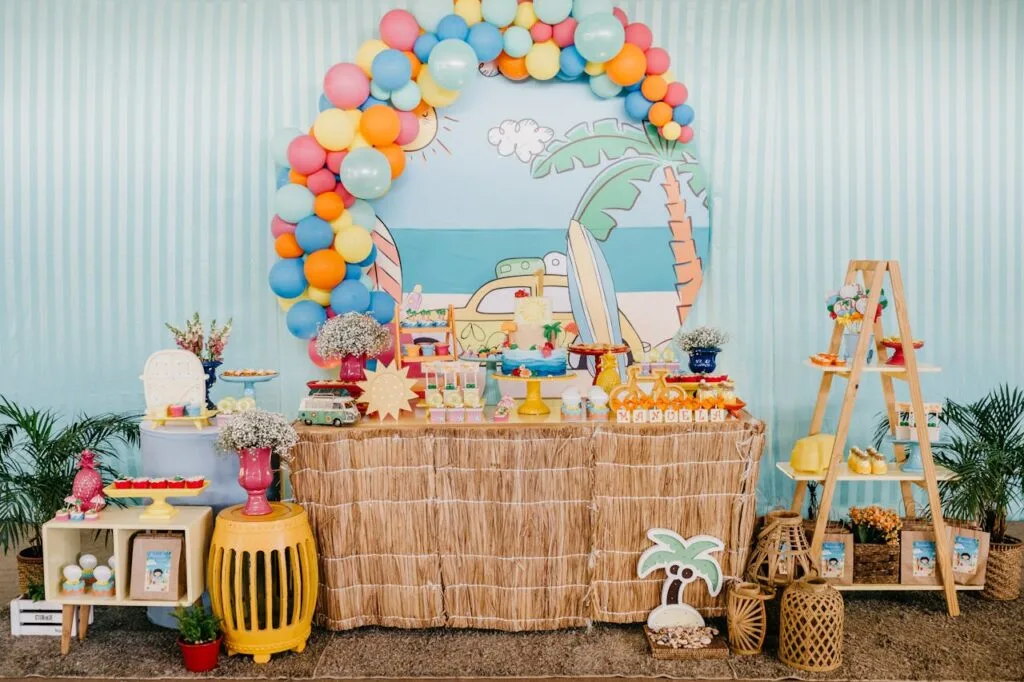 A table set up using budget-friendly summer party decor ideas such as a balloon arch and tropical-themed decorations from around the home .