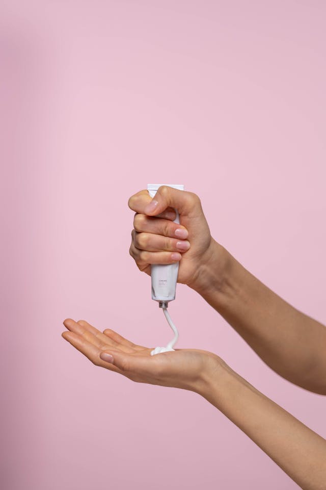 A person squeezing a tube of lotion into her hand