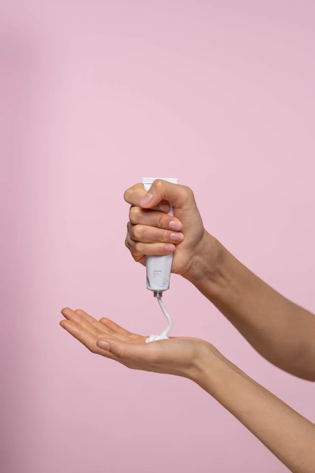 A person squeezing a tube of lotion into her hand