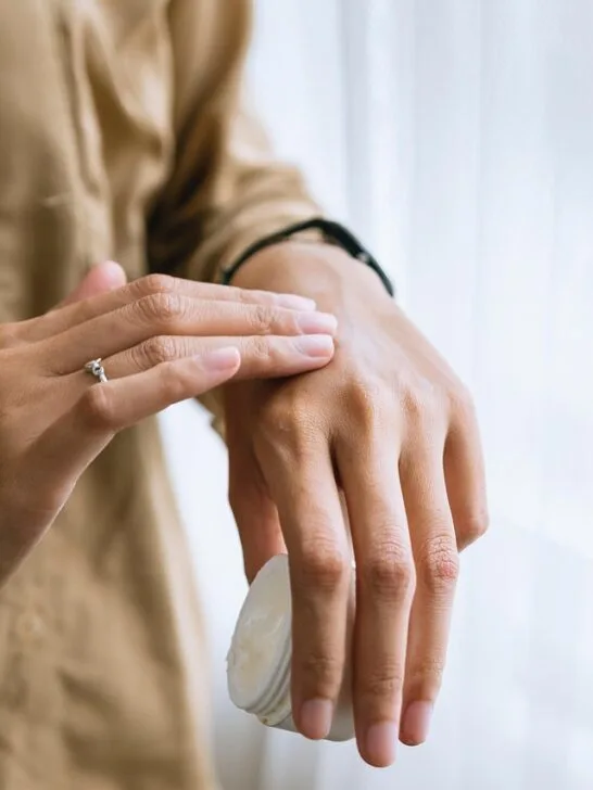 A person applying lotion to the back of their hand as moisturizing is a key part of wrinkle-free skin