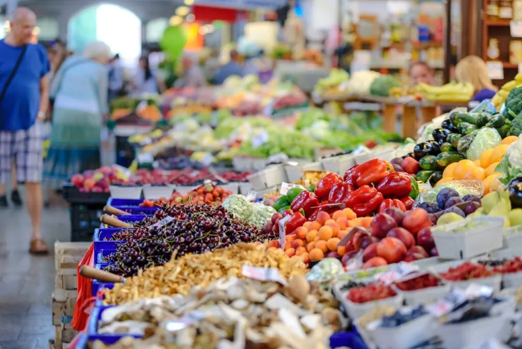 People shopping at a farmers market, one of our easy eco-friendly summer tips for green living.