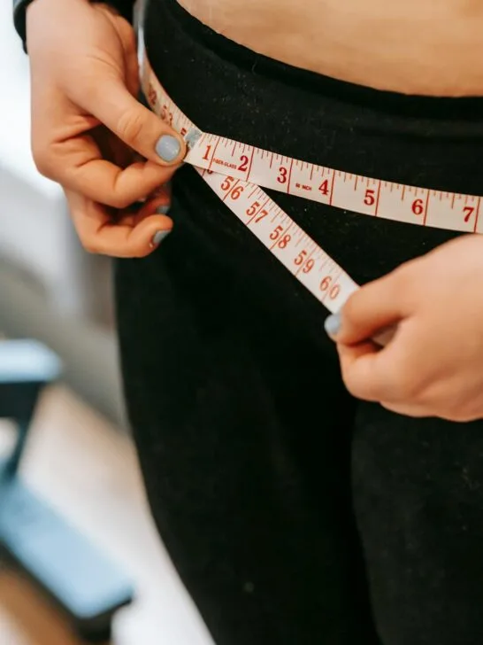 A woman holding a tape measure around her hips