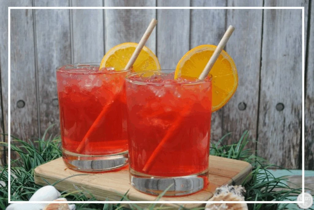 Two Caribbean Punch cocktails garnished with orange wheels and straws