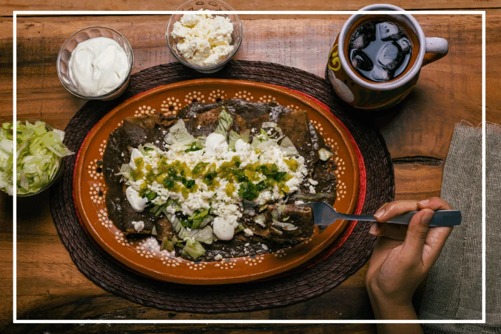 overhead view of a plate of enfrijolados on a red stoneware plate