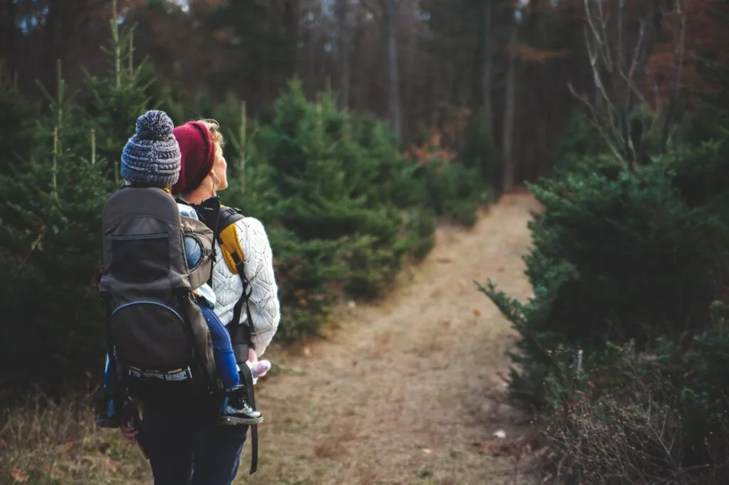 A woman hiking with her toddler in a sling on her back 