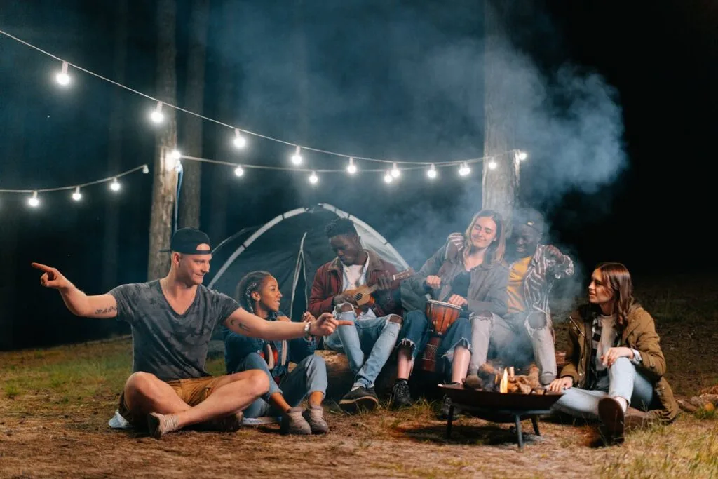 Friends enjoying a campfire at night on a camping trip, showing how well-organized trips create fun and stress-free moments together.